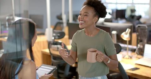 Businesswomen Engaging in Active Work Discussion Over Coffee in Office