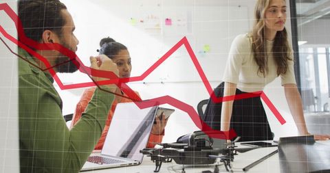 Diverse Team Analyzing Declining Statistical Data in Modern Office