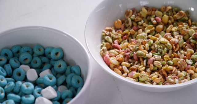 Colorful breakfast cereals presented in white bowls on a white surface. Ideal for use in marketing materials promoting healthy breakfast options, nutritional content, or cereal products. Can also be used in children's food advertising or social media posts highlighting fun and vibrant meal choices.