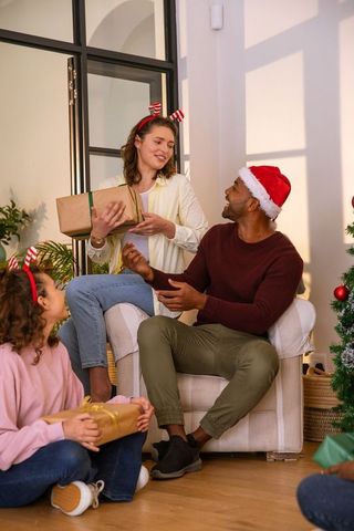 Diverse Family Holiday Gift Exchange by Christmas Tree at Home