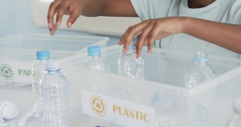 African american boy sorting plastic bottles into recycling bin for classroom learning