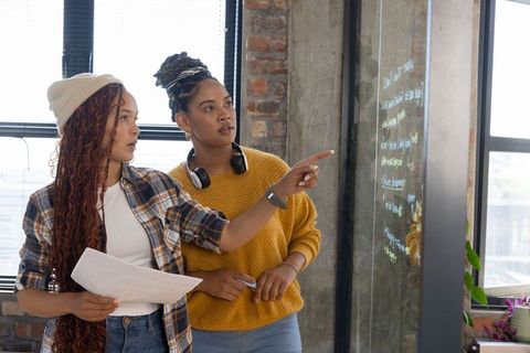Creative coworkers brainstorming ideas at office glass board