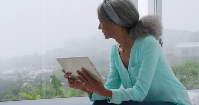 Mature woman with gray hair using tablet in bright modern home - Download Free Stock Images Pikwizard.com