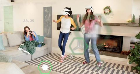 Friends wearing vr headsets playing dance game in cozy holiday living room by fireplace