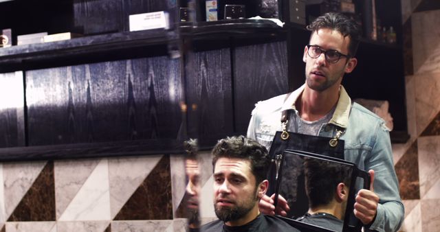 Hairdresser showing client his haircut in mirror at barber shop