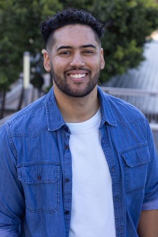 Smiling african american man standing on rooftop in denim shirt and white t-shirt