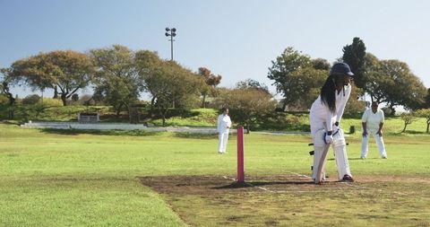 Female Cricket Players in Action with Pink Stumps on Green Field