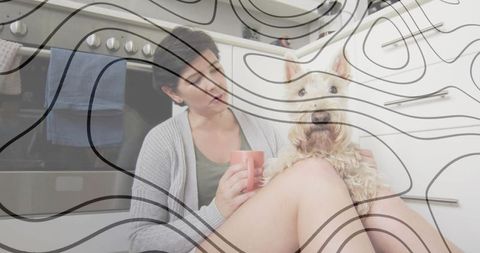Woman relaxing in kitchen with dog and mug