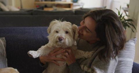 Woman Embracing Fluffy Cream Dog in Cozy Living Room Setting