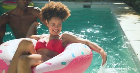 Summer fun african american friends in pool with donut float