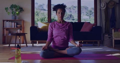Woman Meditating on Yoga Mat in Cozy Home Living Space