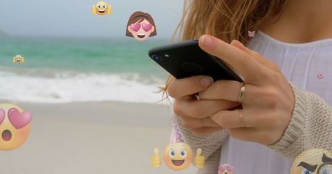 Caucasian Woman Engaging on Smartphone at Beach with Emoticons