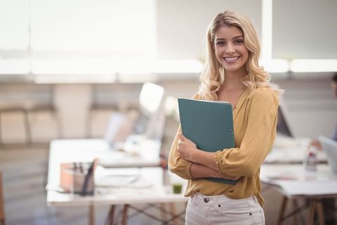 Professional young woman standing confidently in open-plan office