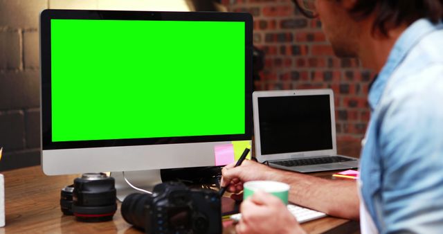 Graphic Designer Working at Computer with Green Screen, Holding Coffee - Download Free Stock Images Pikwizard.com