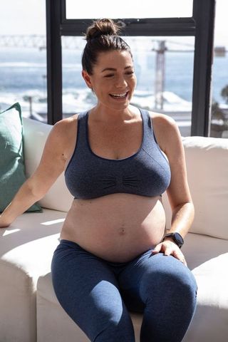 Pregnant Woman Relaxing by Ocean View Window in Comfortable Activewear