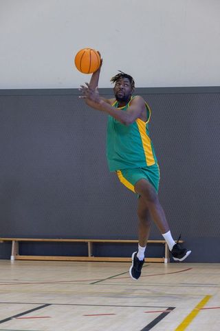 African American Athlete Jumping with Basketball in Gym