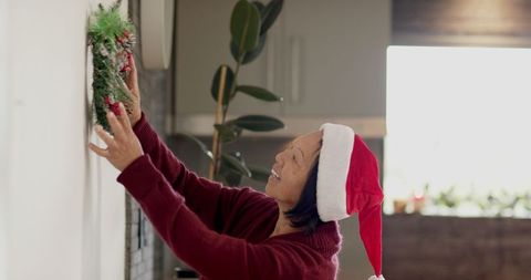 Senior Woman Hanging Festive Wreath in Kitchen