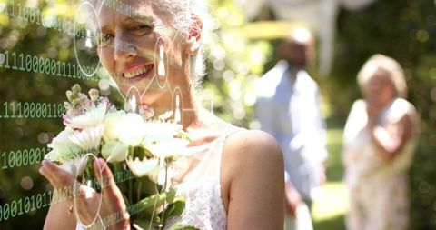 Smiling senior woman holding bouquet in sunlit garden with binary hud overlay