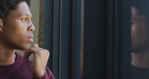 Thoughtful Young Man Reflecting by Window at Home