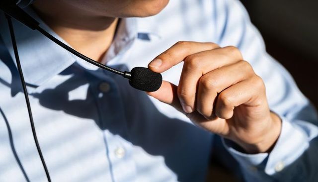 Adjusting headset microphone closeup of professional host in blue shirt for podcasting