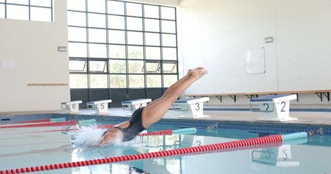 Athlete diving into pool in professional indoor swimming center