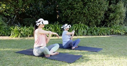 Mother and Daughter Doing Yoga with VR Headsets Outdoors