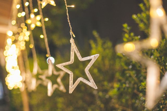 Christmas star decorations hanging with warm lights in background - Download Free Stock Images Pikwizard.com