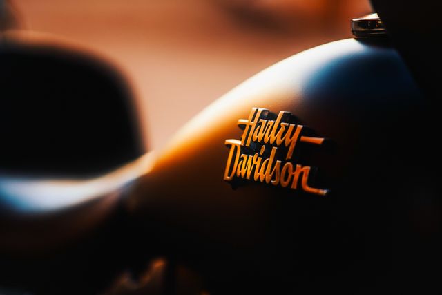 Closer look at the Harley-Davidson logo on a matte black motorcycle fuel tank, perfect for articles or promotions about motorcycle brands, advertisements that focus on iconic transportation vehicles, branding discussions, and lifestyle pieces related to motorcycling.