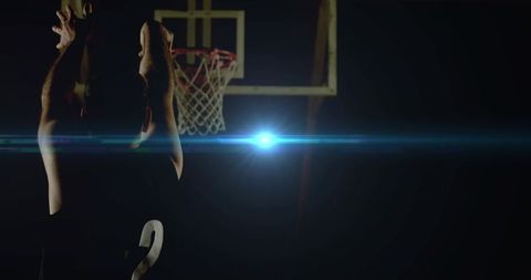 Basketball Player Shooting on Dark Court with Dramatic Lens Flare