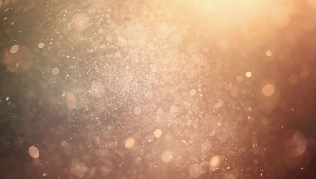 Golden dust particles floating in sunlight with bokeh orbs and warm lens flare