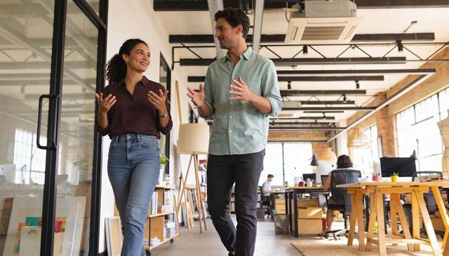 Professionals walking and discussing in modern open-plan coworking office, teamwork