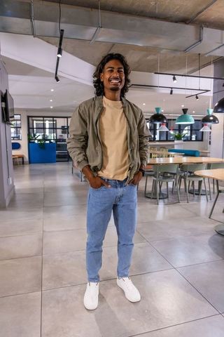 Young Indian professional standing confidently in modern co-working dining area