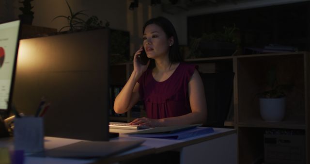Image of asian businesswoman using smartphone, working late in office. Business and working in office at night with technology concept.