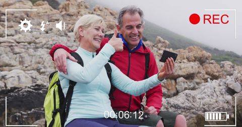 Senior Couple Taking Selfie by Rocky Seaside on Hiking Adventure