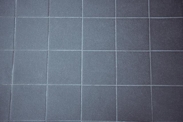 Gray paving stone road background showing uniform square tiles. Ideal for use in architectural designs, urban planning presentations, construction materials catalogs, or as a textured background for graphic design projects.