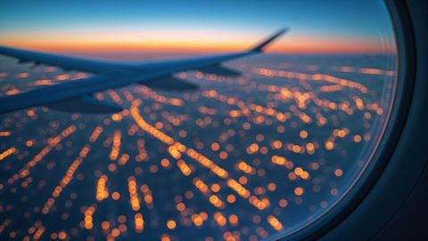 Airplane Wing at Twilight with Bokeh City Lights Below