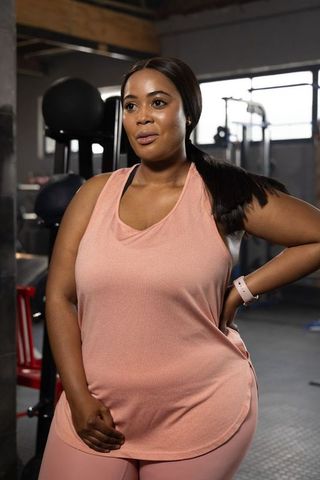 African american woman training in industrial gym wearing pink workout set and smartwatch
