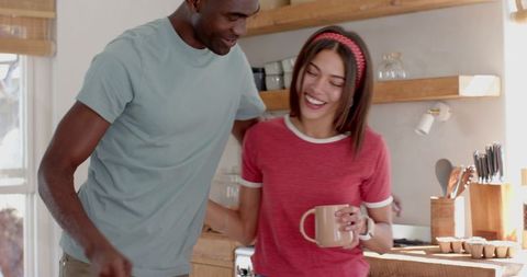 Diverse Couple Joyfully Cooking Together in Bright Home Kitchen