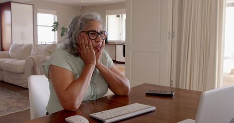 Senior woman surprised while using computer at home office desk