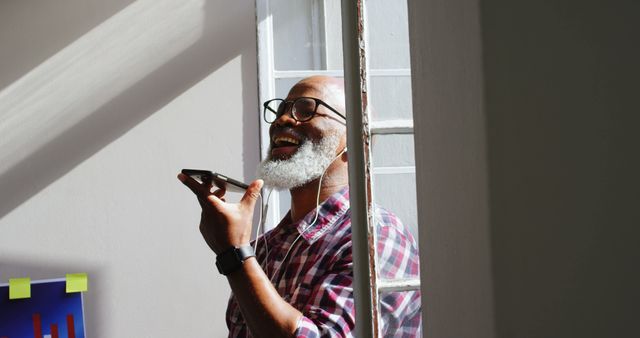 Mature Man Enjoying Phone Conversation in Sunlit Room - Download Free Stock Images Pikwizard.com