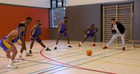 Enthusiastic Basketball Team Training with Coach in Gym
