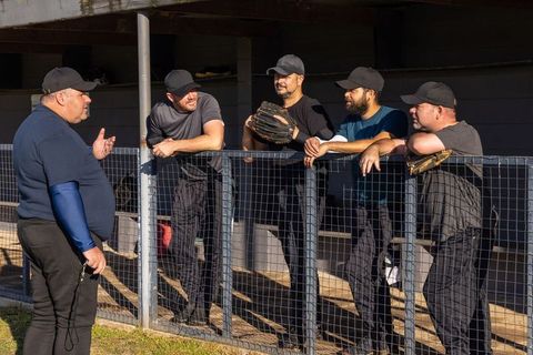 Senior coach leading baseball team discussion in dugout during sunny practice session