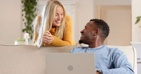 Smiling couple collaborating on laptop in cozy living room