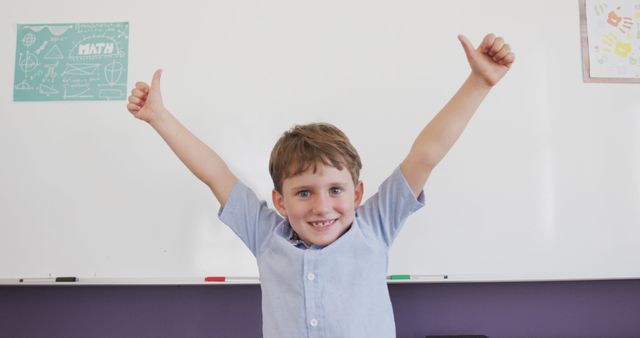 Young boy with brown hair giving a cheerful thumbs up while standing in front of a whiteboard in a classroom. Perfect for education websites, school brochures, and positive learning advertisements.