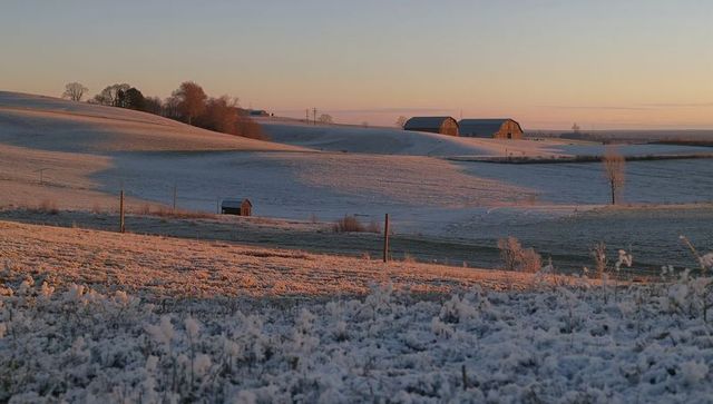 Glistening Frost-Covered Rolling Fields Glowing at Sunrise with Barns on Horizon