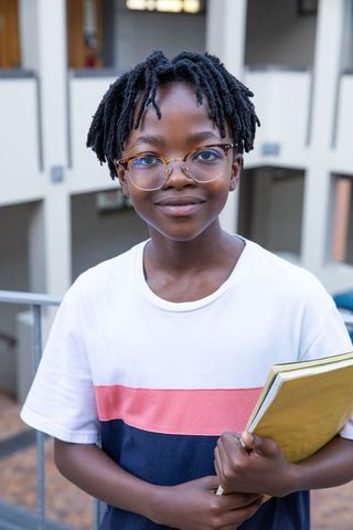 Confident Teen Holding Notebooks in Modern School Corridor