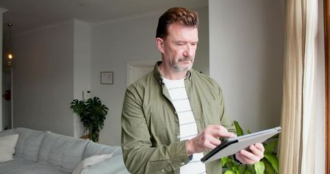 Middle-Aged Man Using Tablet in Modern Minimalist Living Room