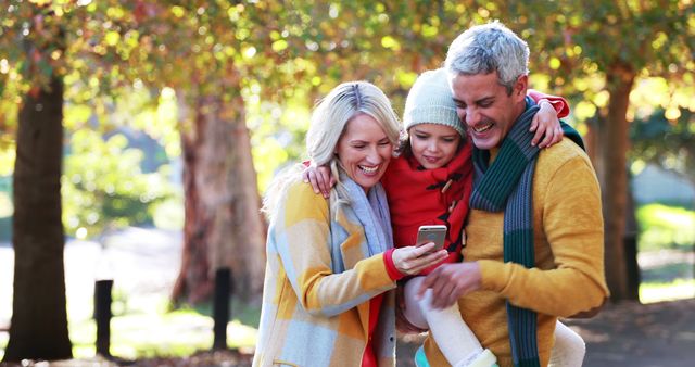 Happy Family Outdoors in Park Using Smartphone on Crisp Autumn Day - Download Free Stock Images Pikwizard.com