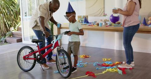 Family celebrating birthday with surprise bicycle gift for child