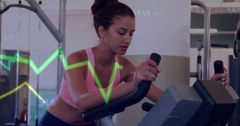 Young woman pedaling on stationary bike tracking performance metrics with neon graph overlay